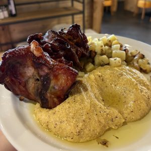 un piatto di spiedo bresciano accompagnato da patate al forno e polenta